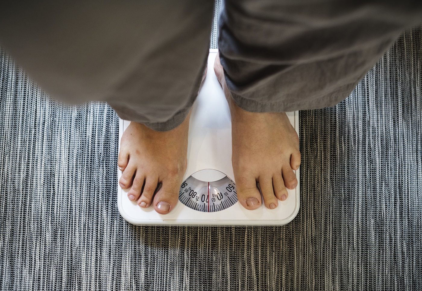 Woman standing on a scale Tips To Overcome A Weight-Loss Plateau | BookDOc