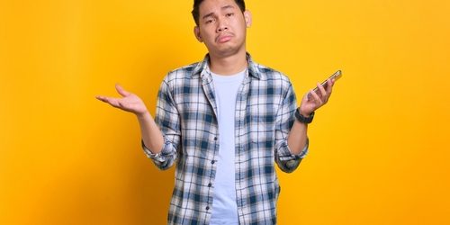 Confused,Young,Asian,Man,In,Plaid,Shirt,Holding,Mobile,Phone